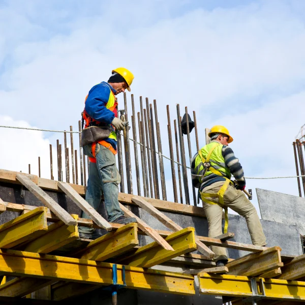 Deux hommes travaillant sur un chantier de construction, manipulant du béton.